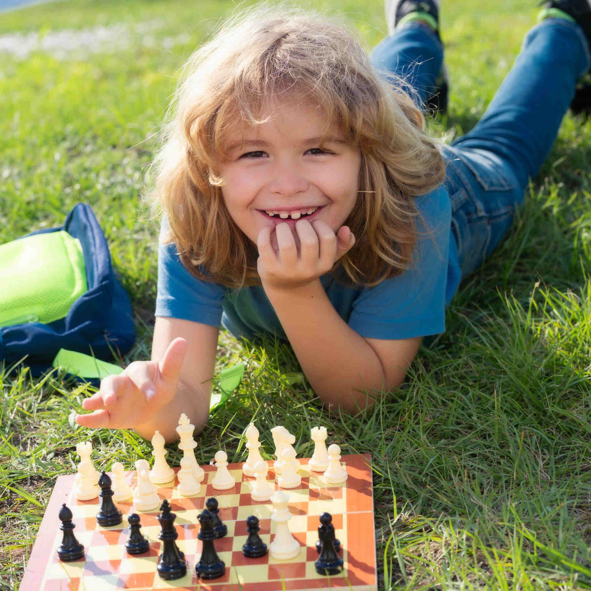 dziecko-mysli-o-szachach-lezacych-na-trawie-w-letnim-parku-koncepcja-uczenia-sie-i-dorastania-dzieci-szachowy-sukces-i-wygrana-gra-na-swiezym-powietrzu-hobby-i-styl-zycia-dzieci_Easy-Resize.com